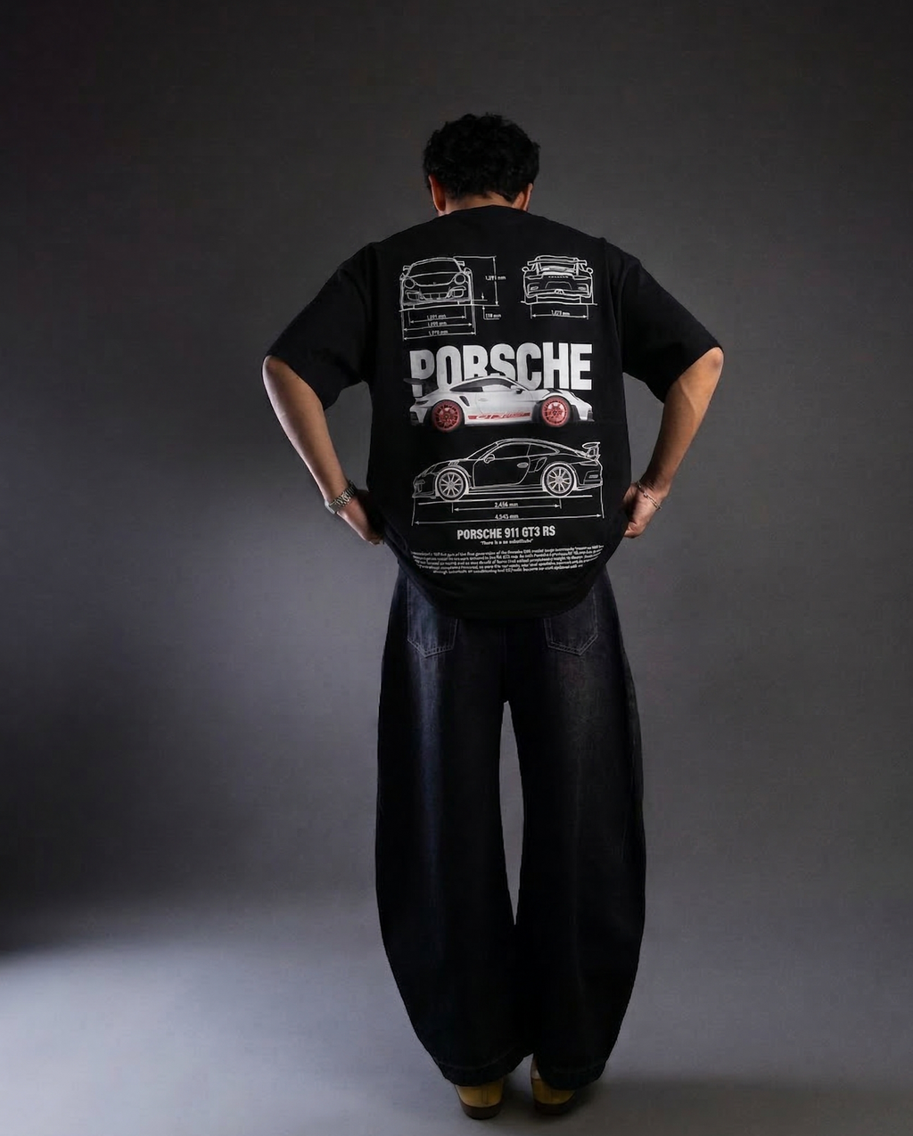 Person wearing a black t-shirt with Porsche design on the back against a gray background